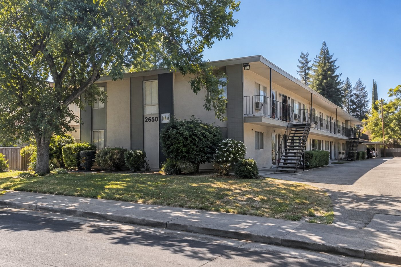 Older two-story apartment building in Northern California with mature trees, representative of the small multifamily properties Dottco acquires