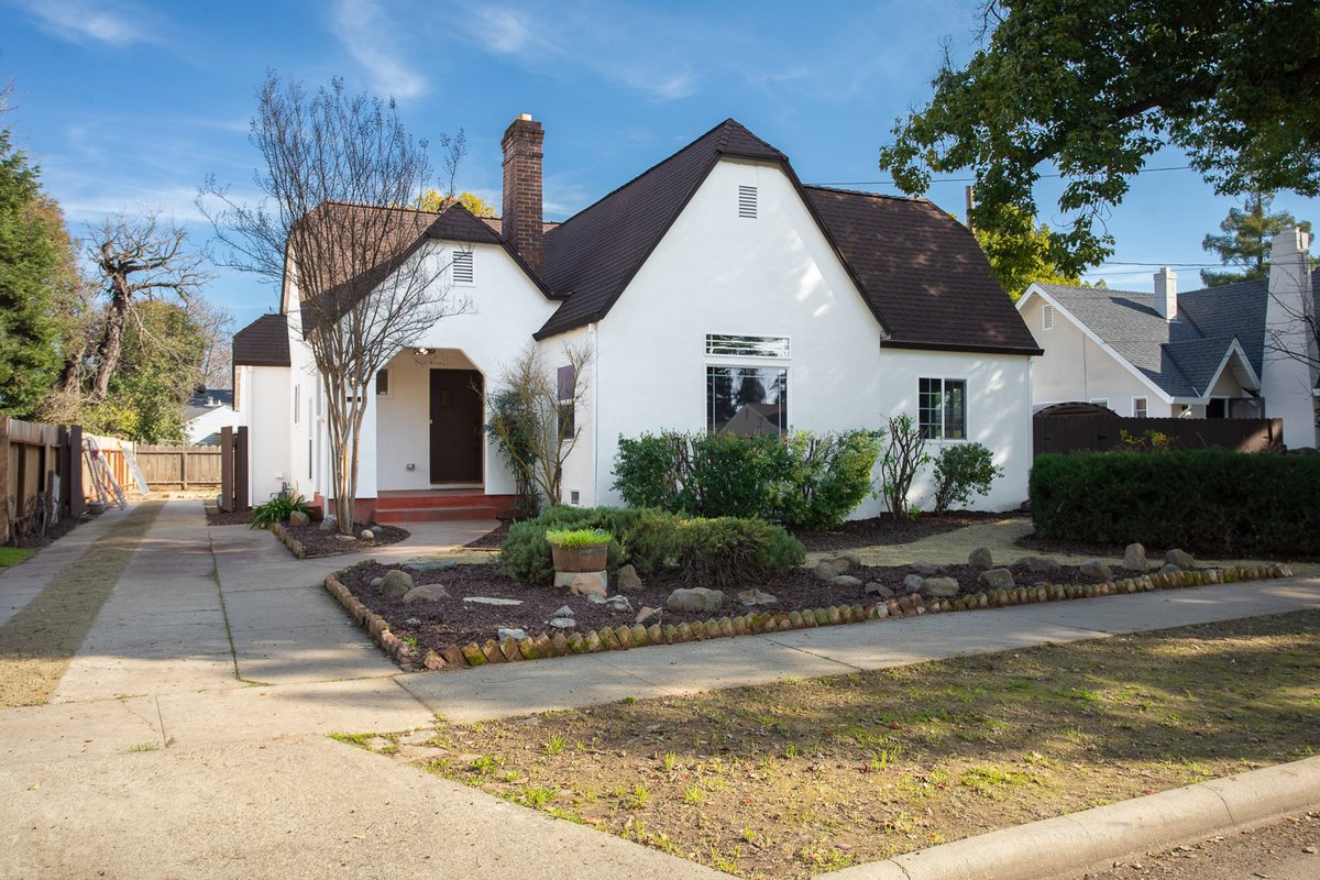 Olive Street after Dottco rehabilitation: fresh white exterior, new dark roof, full new landscaping under a clear sky