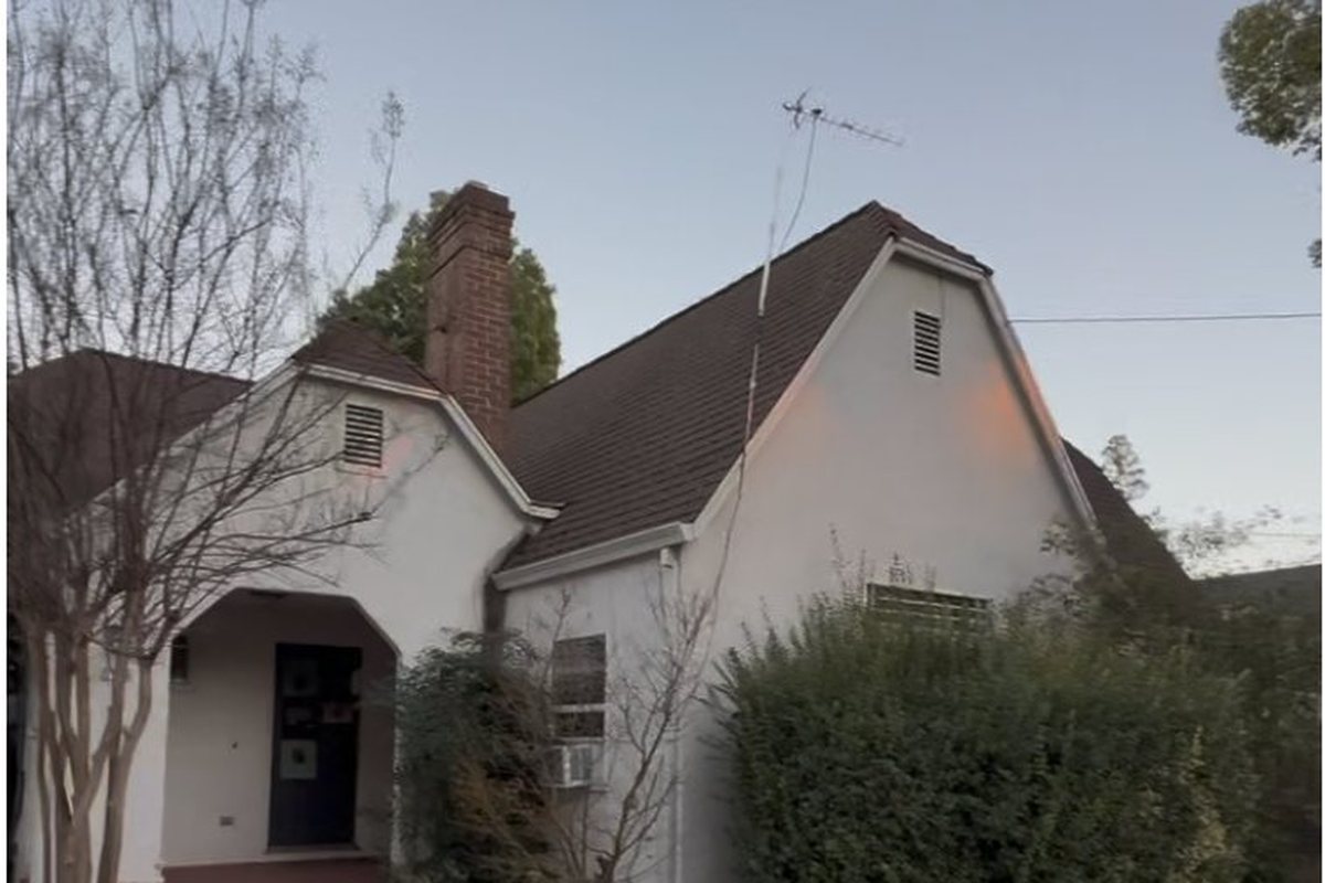 Olive Street before rehabilitation: overgrown shrubs against the house, stained roof, dated exterior at dusk